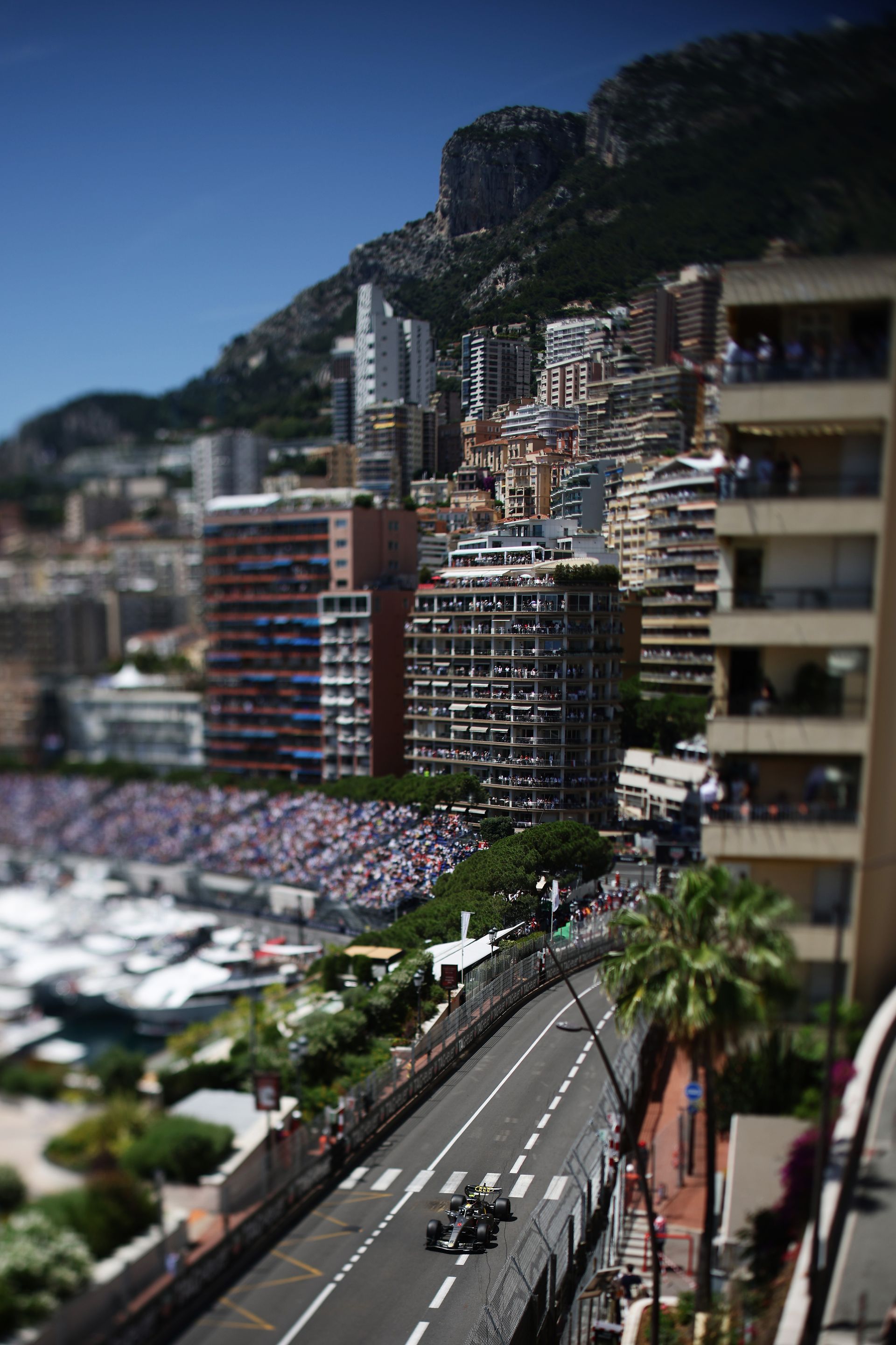 Audi Revolut F1® Team car R26  drives on the Circuit de Monaco featuring big buildings and the spectators arena in the back 