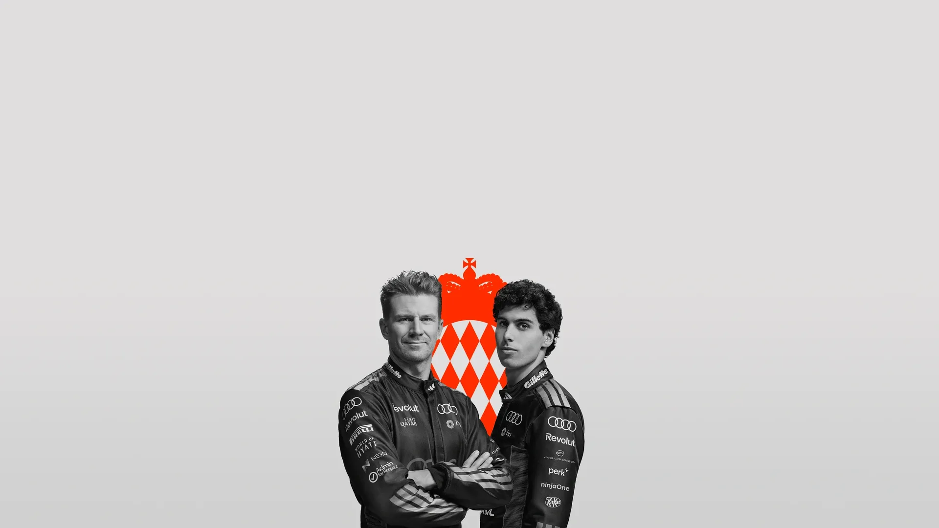 Nico Hulkenberg and Gabriel Bortoleto dirvers at the Audi Revolut F1® Team posing side by side in front of the Moanco Flagin the Studio