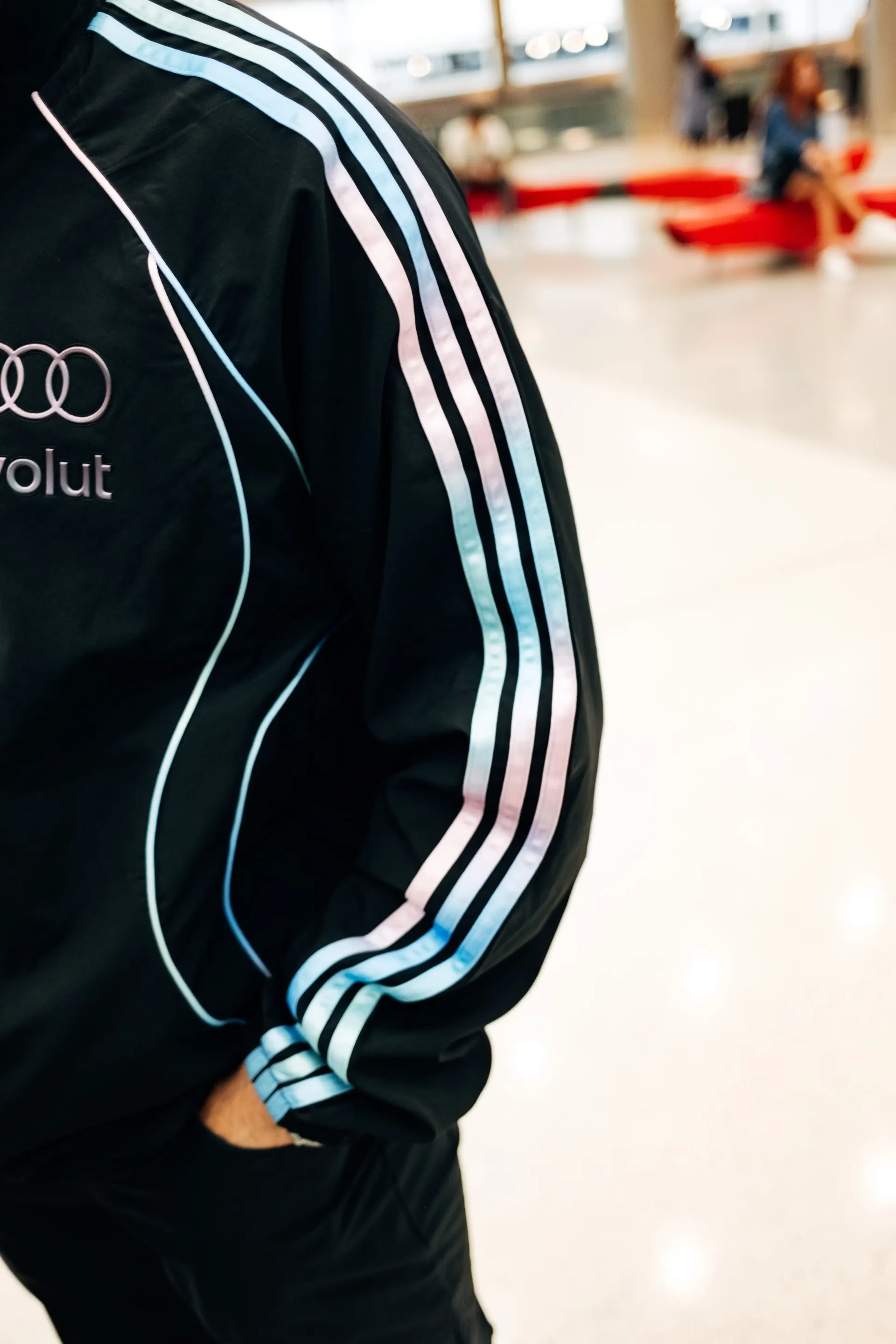 Close-up of Audi Revolut F1®Team crew walking through terminal corridor in the new Miami collection tracksuit.